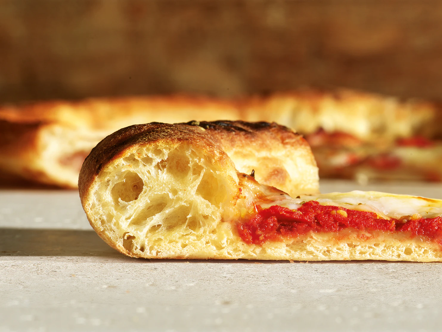 A cut through view of a slice of pizza with a thick crust.