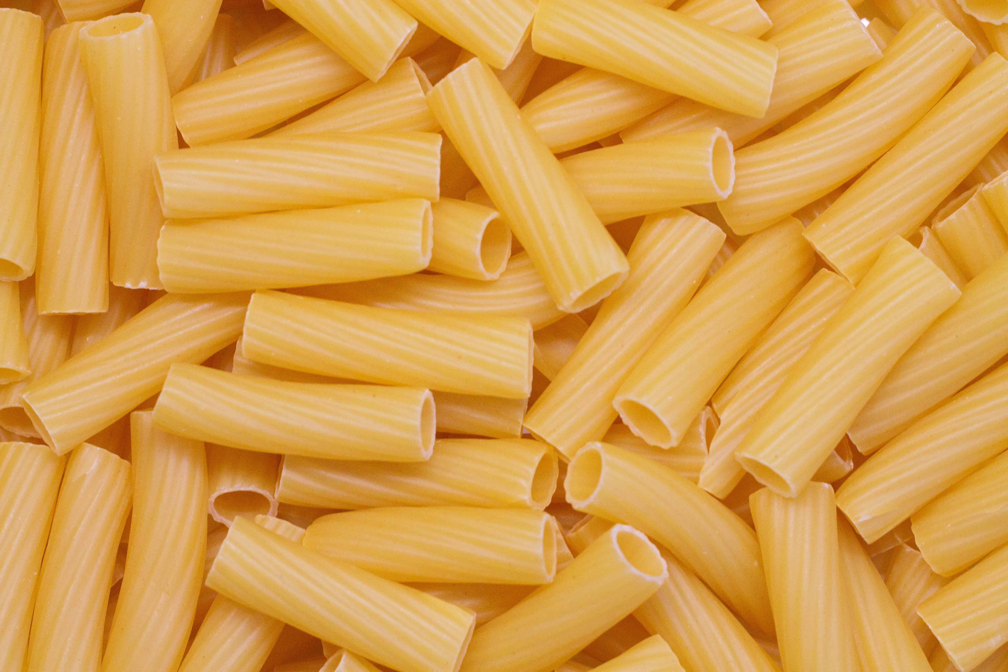 Tubes of yellow rigatoni pasta with light grooves running across each tube.