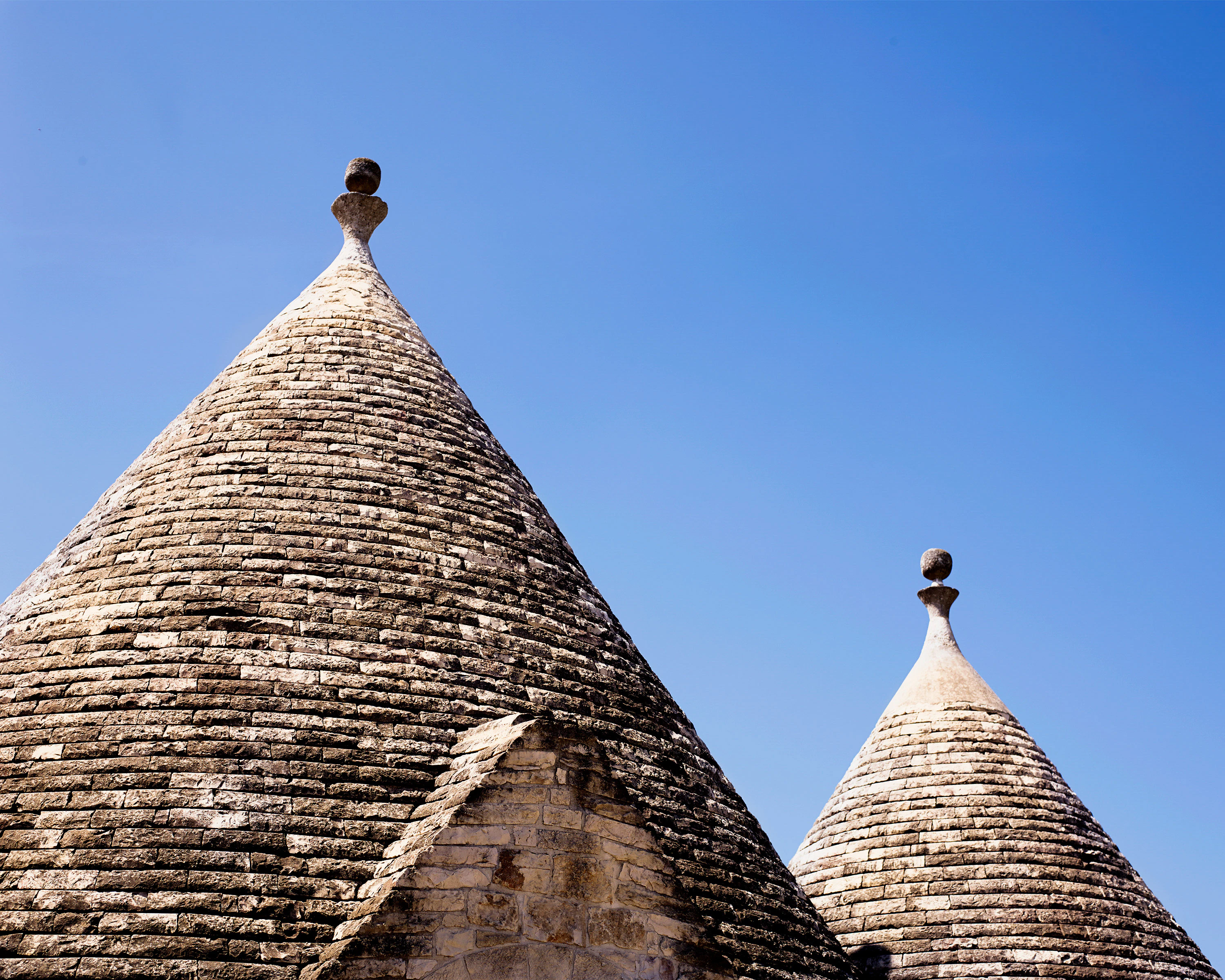 Trullo (traditional Puglian dwellings) )roofs against a blue sky.