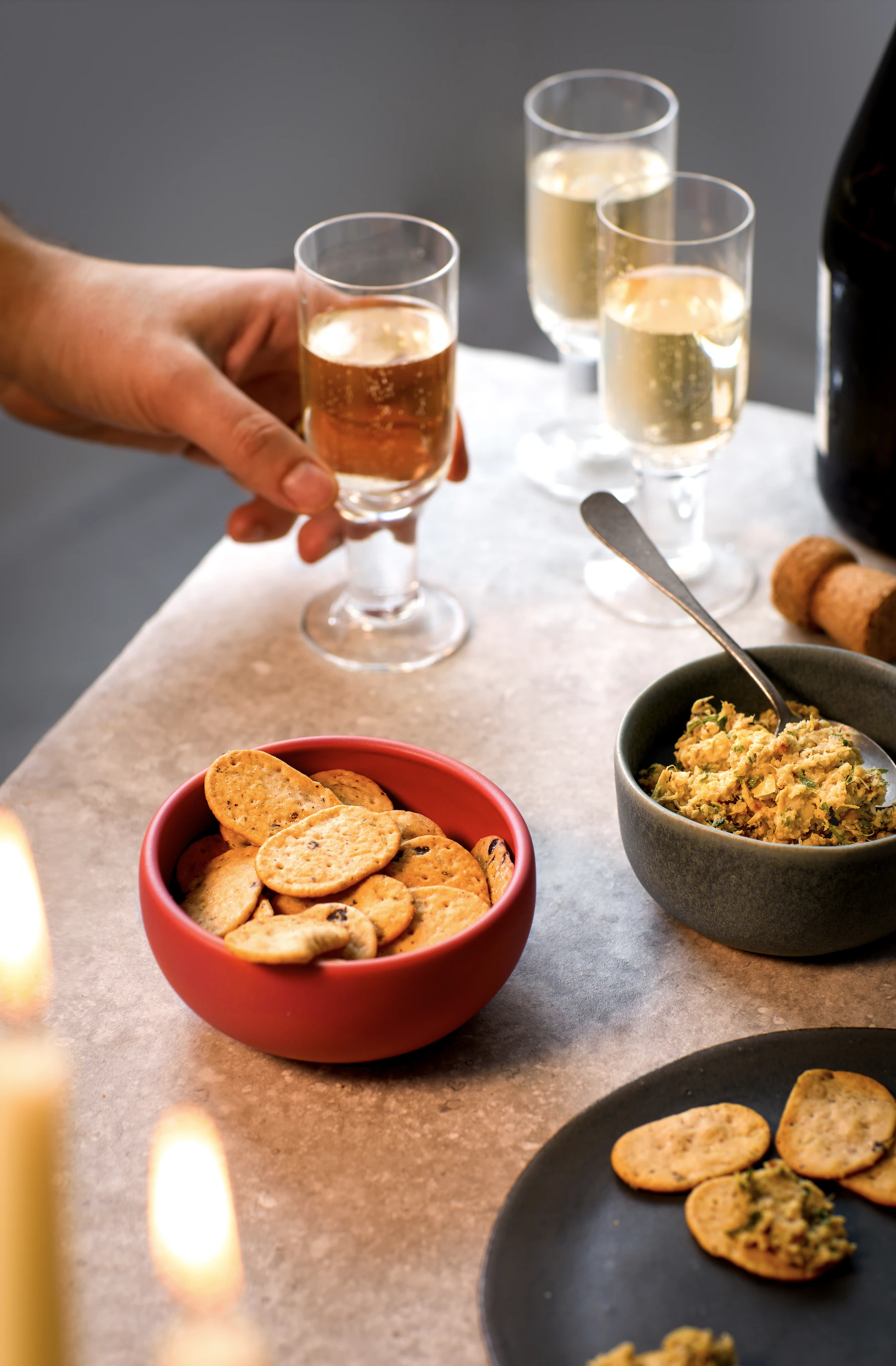Three bowls of nibbles on a table with three glasses of prosecco.