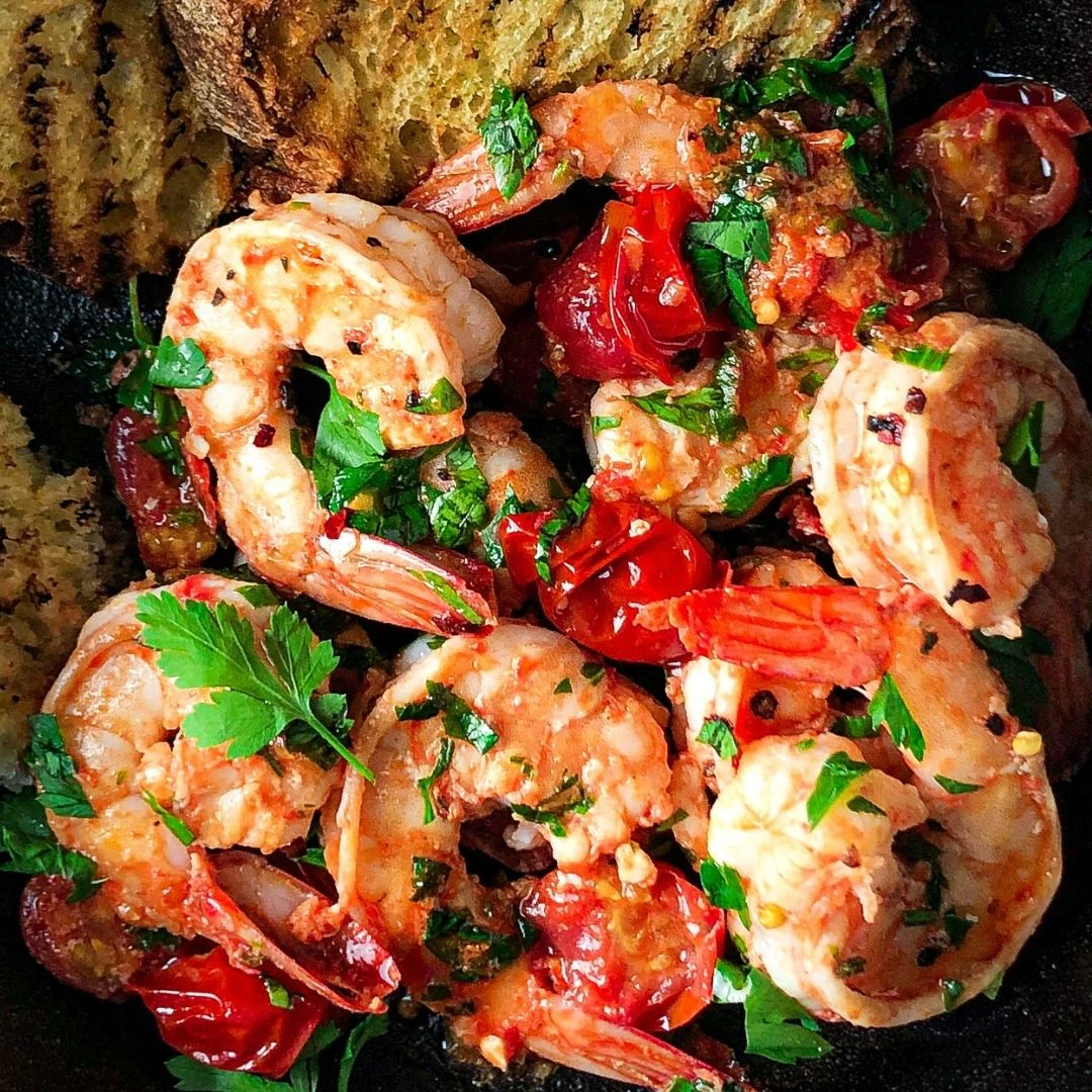 King prawns and pan-fried tomatoes are next to charred Pane Pugliese with fresh coriander on top.