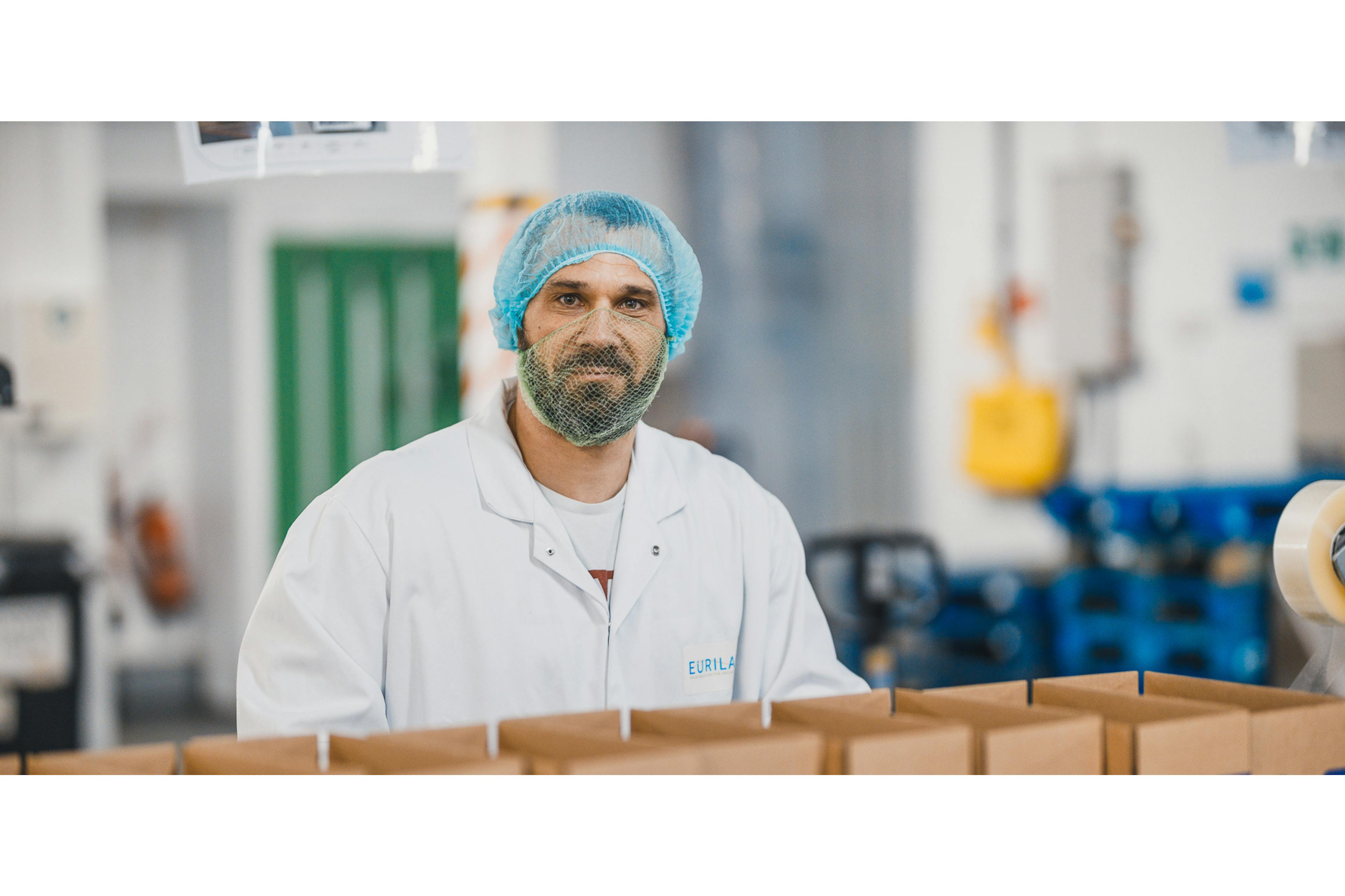 Male factory worker in hair net and white coat