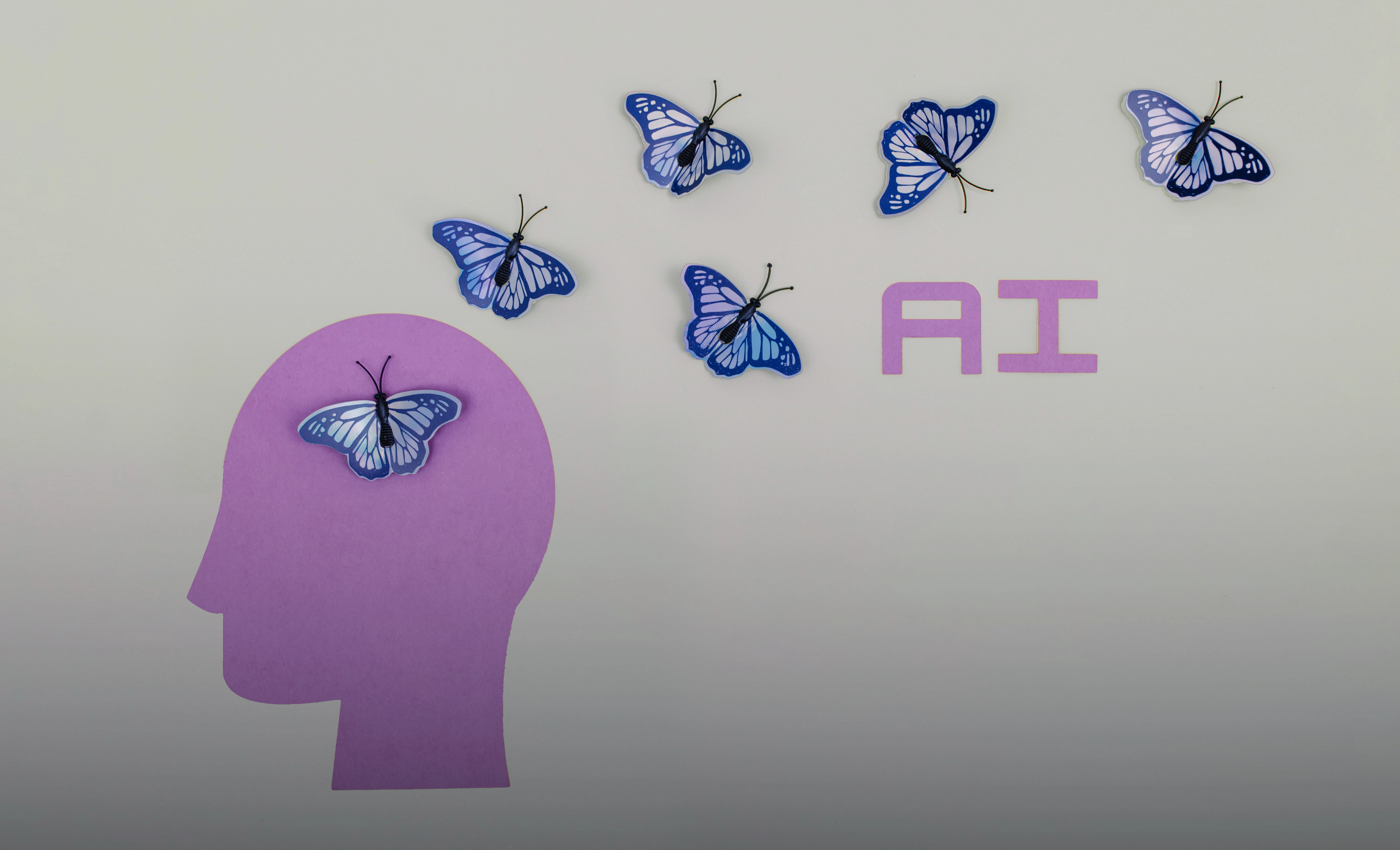A pink graphic image of a head with next to purple butterflies and the letters "AI."