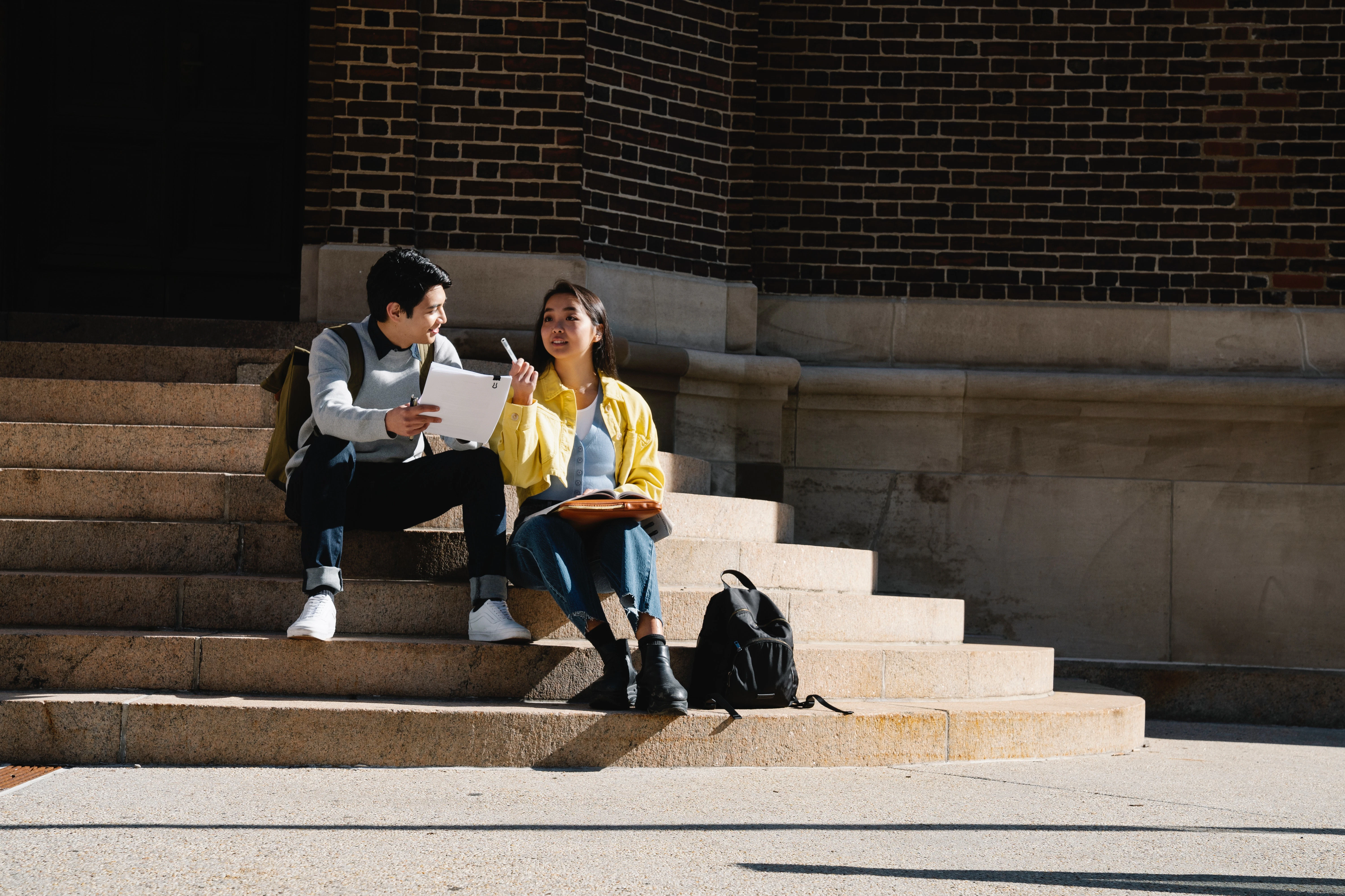 a photo of two students sitting on university steps, having an animated conversation