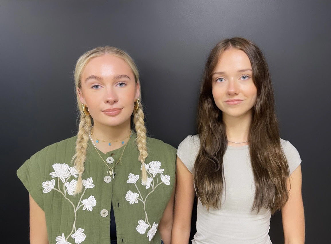 Alex and Eva, our interns, smiling in front of a black wall.