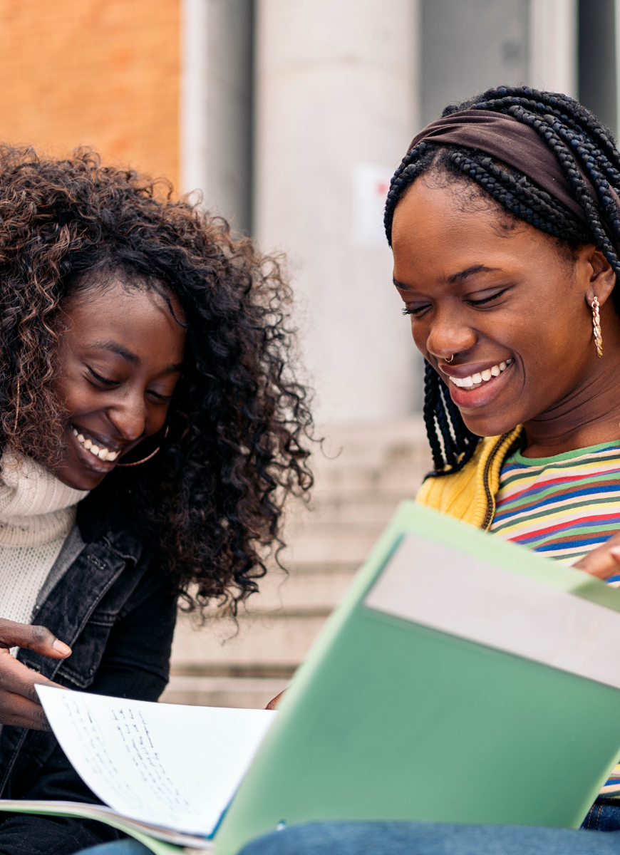  Two students looking at a book smiling