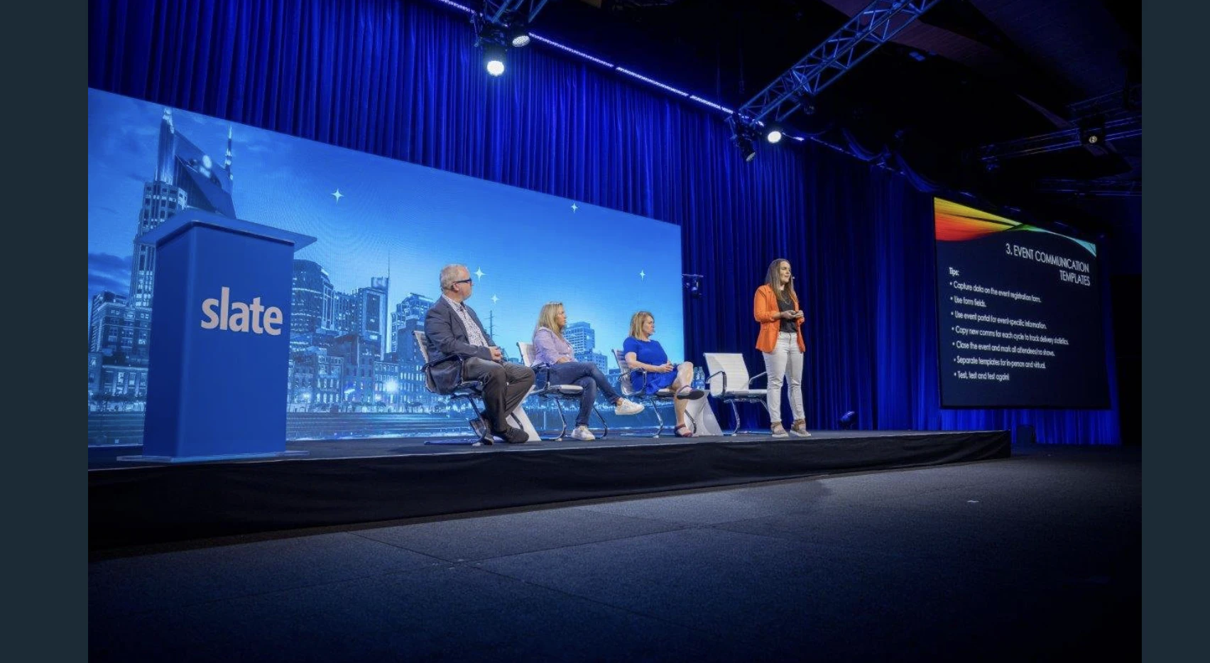4 professionals stood on a Slate stage in front of a blue screen and Slate podium