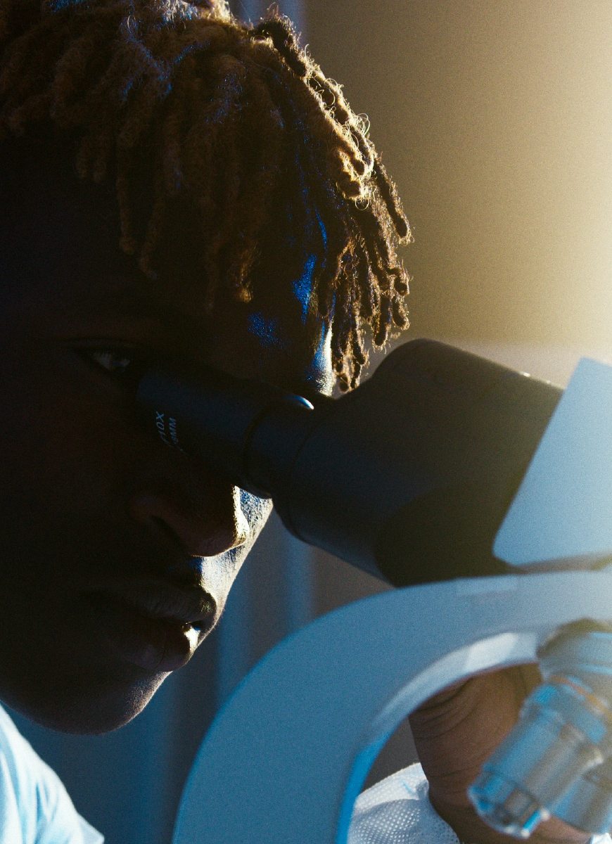 A student looking into a microscope during class at QUB