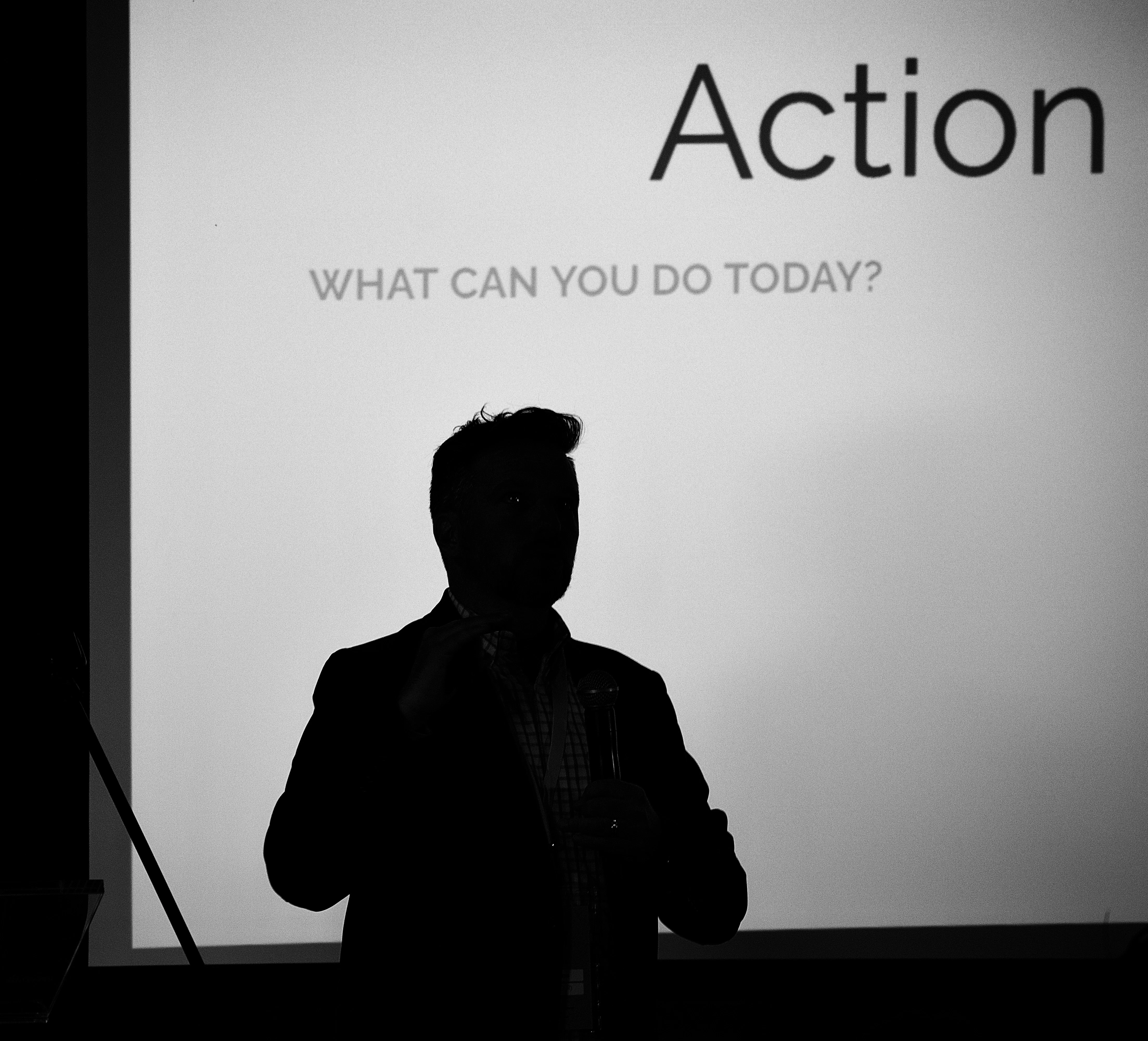 Ken Higgins silhouettes against his screen, which says "Action: What can you do today?"